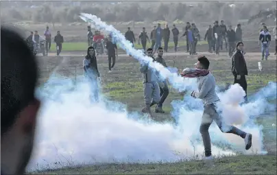  ?? "1 1)050 ?? A Palestinia­n protester throws back a teargas canister that was fired by Israeli soldiers Friday during clashes on the Israeli border following a protest against U.S. President Donald Trump’s decision to recognize Jerusalem as the capital of Israel, east of Gaza City.