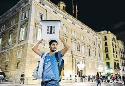  ?? ÀLEX GARCIA ?? Un voluntario del referéndum, en la plaza de Sant Jaume, se lleva una de las urnas de recuerdo