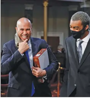  ?? (AP/J. Scott Applewhite) ?? Sen. Cory Booker (left), D-N.J., is shown with a family member Sunday after taking the oath of office from Vice President Mike Pence during a reenactmen­t ceremony in the Old Senate Chamber at the U.S. Capitol.