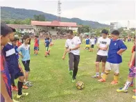  ??  ?? JURULATIH pasukan Sabah Jelius Ating menunjukan cara betul menendang bola kepada para peserta klinik.