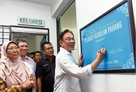  ?? — Bernama ?? Making it official: Anwar signing a plaque after opening the Pahang PKR office in Kuantan. Also present were (from left) Deputy Minister in the Prime Minister’s Department and Kuantan MP Fuziah Salleh as well as Foreign Minister and Indera Mahkota MP Datuk Saifuddin Abdullah.