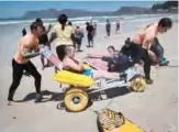  ??  ?? Alison Edwards (54) is helped off the beach after a surf during an adaptive surfing event at Muizenberg beach.