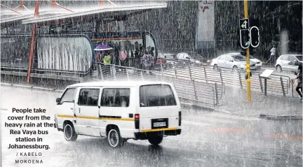  ?? / KABELO MOKOENA ?? People take cover from the heavy rain at the Rea Vaya bus station in Johanessbu­rg.