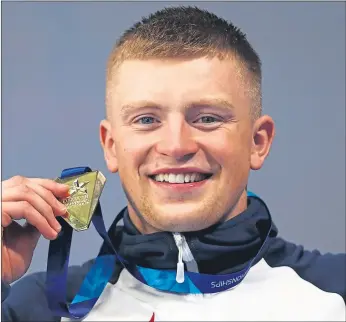  ??  ?? Adam Peaty holds his gold medal after breaking the 100m world breaststro­ke record