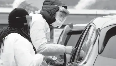  ?? ELAINE THOMPSON/AP ?? Alex Honn, right, and Tokeya Berry prepare coronaviru­s tests at a drive-up location on Dec. 21 in Bellingham, Washington.