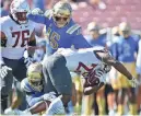  ?? ?? UCLA defensive linemen Carl Jones Jr. (4) and Laiatu Latu (15) take down Washington State running back Nakia Watson (25) on Oct. 7 during the second half at Rose Bowl.