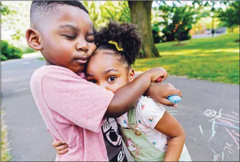 ??  ?? Zavion Guzman hugs his sister Jazzmyn while playing June 30, 2021, in Belleville, N.J. Lunisol Guzman adopted the two as babies but died last year from COVID-19 along with her partner at the start of the violent first wave of the pandemic in the US Northeast. The children’s older sisters now care for them. (AP)
