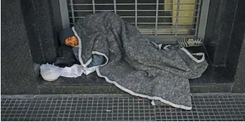  ?? ?? A homeless man sleeps in a doorway on a street in Buenos Aires.