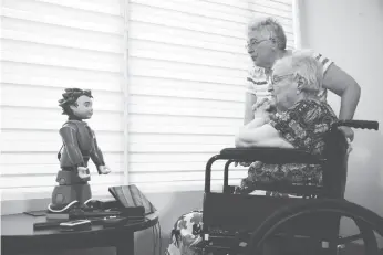  ?? CP PHOTO ?? Elizabeth Graner, who has dementia, sits in her wheelchair as her daughter Penny Blake helps her interact with Ludwig, a two-foot-tall robot created by University of Toronto researcher­s to engage people with Alzheimer’s disease and dementia, at a press...