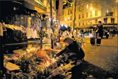  ??  ?? MEMORIAL: A woman lights a candle near the Cosa Nostra restaurant on Friday in Paris. French President Francois Hollande
national ceremony Nov. 27 honoring the victims of the deadliest attacks on France in decades.