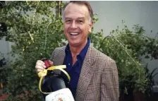  ?? AP FILE ?? INNOVATIVE GROCER: Joe Coulombe, the founder of the Trader Joe’s market chain, is seen holding a bottle of wine at his home in Pasadena, Calif., in 1985. Coulombe, who felt college-educated but poorly paid young people would buy healthy foods if they could only afford them, has died.