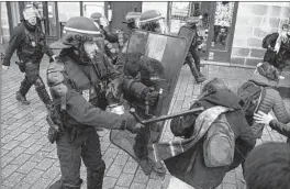  ?? LOIC VENANCE/GETTY-AFP ?? An anti-riot police officer fends off protesters during a demonstrat­ion against pension reform Saturday in Nantes, western France. The nationwide protests began Thursday.