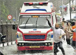  ?? ANI ?? People make way for an ambulance through waterlogge­d roads during heavy rainfall in Mumbai. Heavy rain, coupled with thundersto­rms and strong winds, lashed the city and its suburbs early on Saturday, leading to disruption of train and bus services. A BMC statement said the flood rescue squads from the fire brigade had been deployed in six control rooms, while the storm water drain department had checked and verified the working at all six pumping stations as well as that of the pump sets installed in several flood-prone parts of the city.