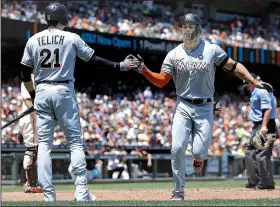  ?? AP/BEN MARGOT ?? Miami outfielder Giancarlo Stanton (right) is met by Christian Yelich after hitting the first of his two home runs in a 10-8 victory over San Francisco in 11 innings. Stanton is expected to show plenty of power in tonight’s MLB Home Run Derby in...