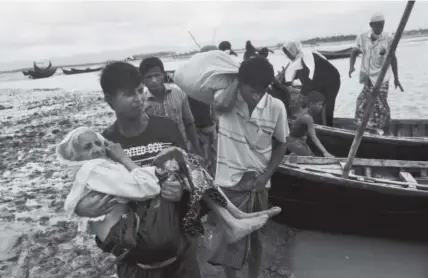  ?? Bernat Armangue, The Associated Press ?? A member of the Rohingya ethnic minority of Myanmar carries an elderly woman after they used a boat to cross a river to reach the Bangladesh side of the border Saturday.