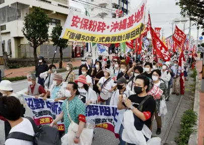  ?? Kyodo News via The Associated Press ?? Protesters march, opposing to the ceremony marking the 50th anniversar­y of its return to Japan after 27 years of American rule, in Ginowan, Okinawa, on Sunday.