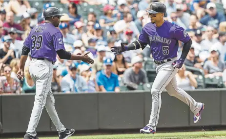  ?? Stephen Brashear, Getty Images ?? Rockies right fielder Carlos Gonzalez is congratula­ted by thirdbase coach Stu Cole after hitting a solo home run during the fifth inning of Sunday’s game at Safeco Field against the Mariners. It was Gonzalez’s eighth home run of the season.