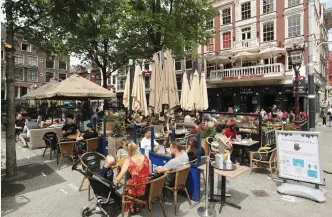  ?? (Eva Plevier/Reuters) ?? CUSTOMERS DINE yesterday at a newly reopened restaurant at Leidseplei­n Square in Amsterdam.