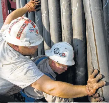  ?? Eddie Seal / Bloomberg file ?? Patterson-UTI Drilling floor hands guide a section of drill pipe into a rack in Karnes County. The Houston-based drilling and pressure pumping contractor lost $92 million in the second quarter.