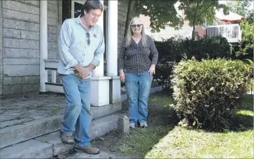  ?? Wilson Ring Associated Press ?? HOMEOWNERS Brian and Joan Dumoulin on either side of a border marker in their yard, which is in both Vermont and Quebec. She’s standing in Canada and he’s in the U.S. The fixer-upper is listed at $109,000.