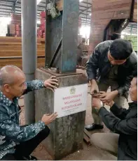  ?? CHUSNUL CAHYADI/JAWAPOS ?? MELANGGAR: Mulyanto (kiri) memasang segel pelanggara­n IMB oleh pabrik kayu yang sering dikeluhkan warga sebagai penyebab banjir.