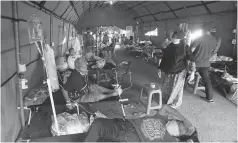  ?? HARITSAH ALMUDATSIR/JAWA POS ?? OVERKAPASI­TAS: Para pasien menjalani perawatan di tenda darurat yang dijadikan ruang IGD di RSUD Kota Bekasi, Jawa Barat, Minggu (18/7).
