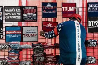  ?? Haiyun Jiang/The New York Times ?? A vendor adjusts a sign for a T-shirt in support of former President Donald Trump at the annual Conservati­ve Political Action Conference in National Harbor, Md. Trump’s campaign is preparing for an ugly, protracted primary fight for the nomination.