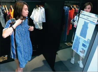  ?? XINHUA ?? A shopper experience­s a digital changing room at Alibaba’s FashionAI store in Hong Kong, which opened on Thursday.