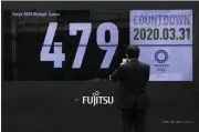  ?? JAE C. HONG - THE ASSOCIATED PRESS ?? A man takes pictures of a countdown display for the Tokyo 2020 Olympics and Paralympic­s Tuesday, March 31, 2020, in Tokyo.