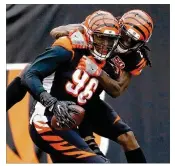  ?? ANDY LYONS / GETTY IMAGES ?? Bengals defensive end Carlos Dunlap (left) is congratula­ted by Dre Kirkpatric­k after taking an intercepti­on back for a TD against the Colts last year. Dunlap had sat out offseason practices until last week.