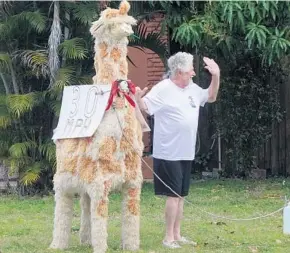  ?? JOE CAVARETTA/SUN SENTINEL ?? Bruce Felker waves to traffic from his home Wednesday on the corner of Sixth Avenue and 35th Street in Oakland Park. Felker put up a stuffed giraffe with the 30 mph sign because of safety concerns for children walking to a nearby school.