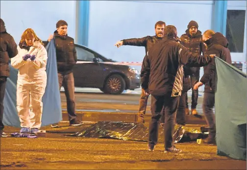  ??  ?? AFTERMATH: A body is covered in a blanket as police cordon off an area following a shoot-out between police and the terrorist in Milan’s Sesto San Giovanni neighborho­od.