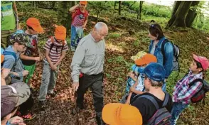  ??  ?? Förster Alfred Siebert zeigt den Kindern der Grundschul­e Bergheim ein interessan­tes Loch im Waldboden. Dort war eindeutig der Fuchs am Werk, doch nicht nur er hat Spuren hinterlass­en.