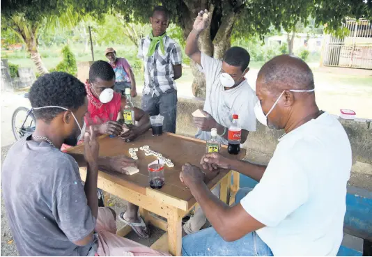  ?? FILE ?? Men wearing dust masks while playing dominoes along the New River Road in Santa Cruz, St Elizabeth on Friday, March 27.