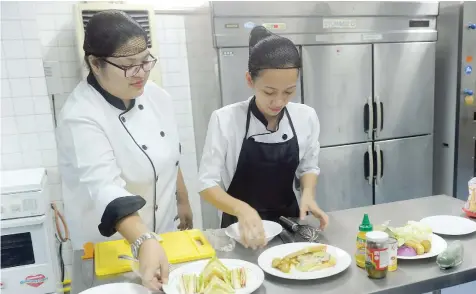  ??  ?? Trainee cooks make a sandwich at a cooking school in Manila