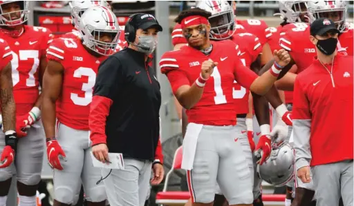  ?? AP ?? Ohio State coach Ryan Day ( talking with quarterbac­k Justin Fields) tested positive for the coronaviru­s. The Buckeyes had to cancel their game against Illinois.