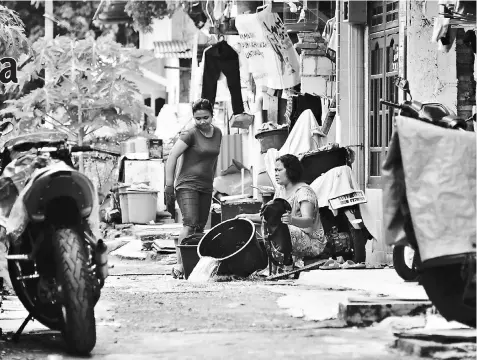  ??  ?? In this photograph taken on Jan 31, residents wash their clothes in front of their house in the Tongkol kampung in Jakarta.