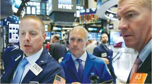  ?? (Brendan McDermid/Reuters) ?? TRADERS WORK on the floor of the New York Stock Exchange yesterday. Oil prices fell to twoand-a-half-month lows amid worries that a global glut of crude and refined products will weigh on markets for some time.