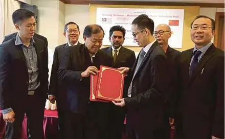  ?? PIC BY ZUNNUR AL SHAFIQ ?? Metronic Global executive director Ric Koh (third from right) exchanging documents with MB Longji Holding managing director Datuk Ng Kek Kiong at the signing ceremony between the two companies in Petaling Jaya yesterday.