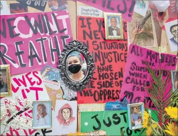  ?? Brian van der Brug Los Angeles Times ?? ARTIST SIERRA HOOD is ref lected in a mirror on her “Pray for the Hood” altar at 43rd Street and Degnan Boulevard. The Juneteenth art installati­on includes protest signs and photos of people killed by police.