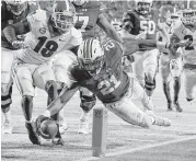  ?? Kevin C. Cox / Getty Images ?? Auburn running back Kerryon Johnson dives for a touchdown while Georgia’s Deandre Baker, left, can do little but look on.