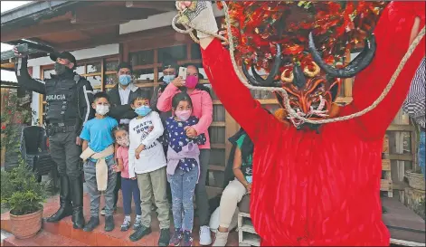  ??  ?? A family watches a person perform dressed as a devil.