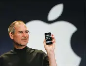  ?? ASSOCIATED PRESS ?? IN THIS 2007 FILE PHOTO, Apple CEO Steve Jobs holds up the new iPhone during his keynote address at MacWorld Conference & Expo in San Francisco. Apple has become the world’s first company to be valued at $1 trillion, the financial fruit of tasteful...