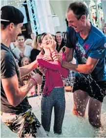  ??  ?? Attendance numbers at St Matthias Church in Plymouth have rocketed, thanks to rappers, above, dance music, and a confetti cannon, above right. Left, a young girl laughs as she is baptised by vicar Olly Ryder, 44, on the right. Young musicians, below, getting the Christian message across at a service