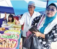  ??  ?? HAJI Hassan (dua kanan) bersama isterinya membeli juadah di bazar itu.