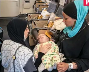  ?? ?? Care: A doctor assesses baby Zain, held on the flight by mum Areej