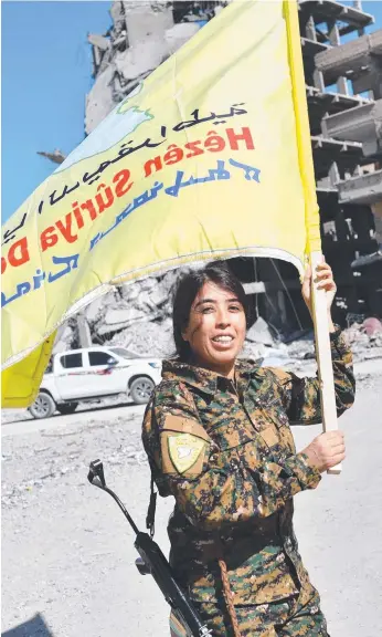  ?? Picture: AFP ?? Commander Rojda Felat waves the SDF flag at Al-Naim square in Raqa.