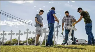  ?? AUSTIN AMERICAN-STATESMAN ?? (From left) Jacob Kubena, his brother Zachary, Doug John and his son Shelby set up a memorial of 26 crosses near First Baptist Church in Sutherland Springs, Texas, on Monday.