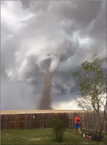  ?? The Canadian Press ?? Theunis Wessels mows his lawn at his home in Three Hills, Alta., with a tornado in the background on Friday.