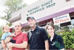  ?? Arnold Gold / Hearst Connecticu­t Media ?? Julie Louizos, right, is photograph­ed with her father, Peter Demetropou­los, left, who is holding her son, Panos, 16 months, and husband, Saki, in front of Whitney Donut & Sandwich Shop in Hamden in August 2020, its 40th year. Julie took over the establishm­ent from her parents.